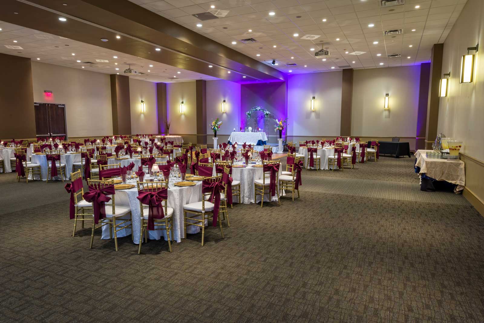 Red Oak Ballroom in Austin, chiavari chairs with ties, plate chargers, stage with head table and arch